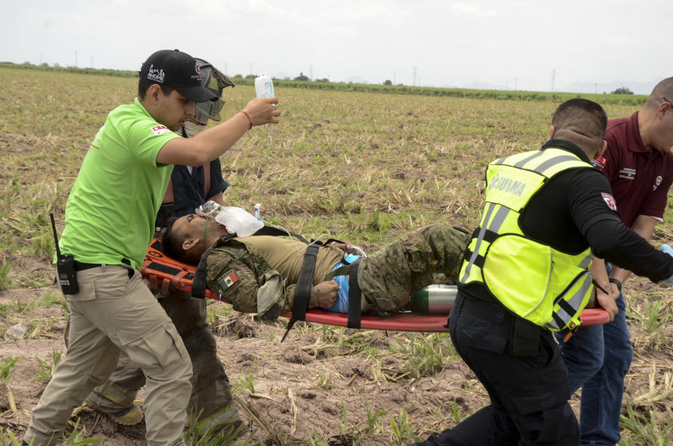 Emergency workers evacuated an injured from a navy Blackhawk helicopter crashed after supporting those who conducted the capture of drug lord Rafael Caro Quintero, near Los Mochis, Sinaloa state, Mexico, Friday, July 15, 2022. Mexico's navy said multiple people aboard died. (AP Photo/Guillermo Juarez)