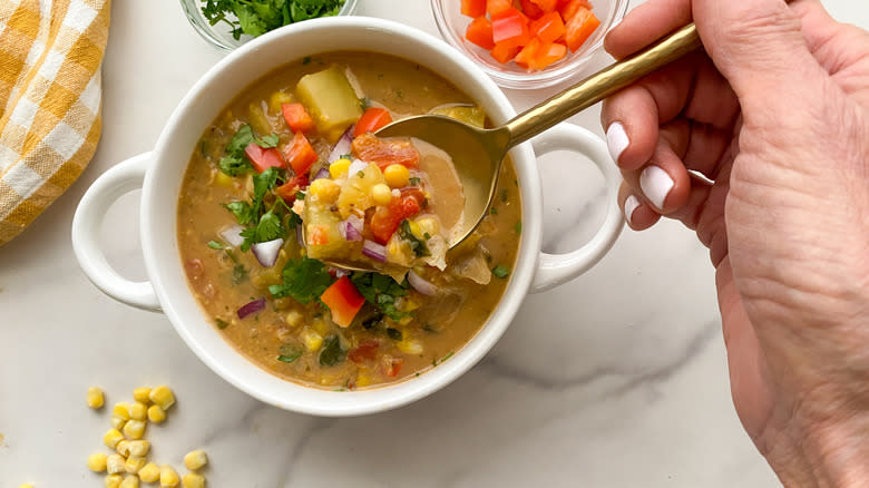 Plant-based corn chowder in white bowl with spoon