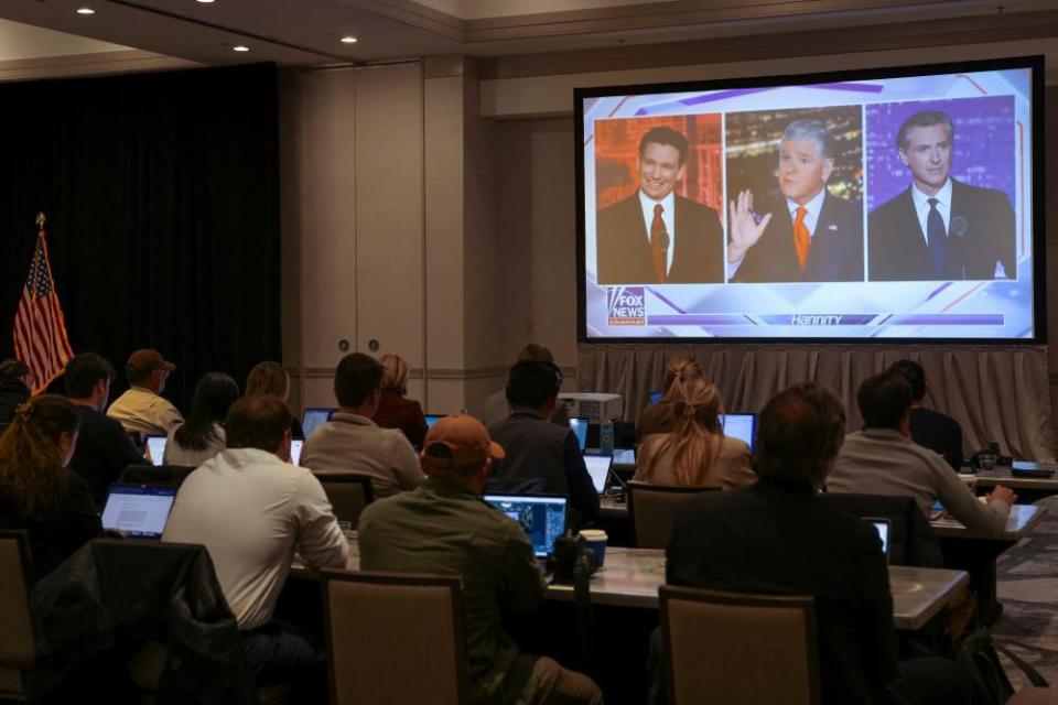 Journalists watch Ron DeSantis debate Gavin Newsom on a screen in the media room, in Alpharetta, Georgia.