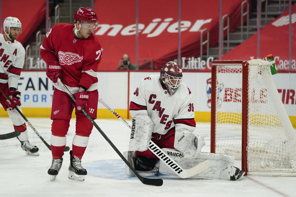 Carolina Hurricanes goaltender Alex Nedeljkovic (39) stops a shot as Detroit Red Wings left wing Adam Erne (73) watches for a rebound in the second period of an NHL hockey game Sunday, March 14, 2021, in Detroit. (AP Photo/Paul Sancya)