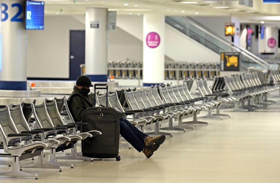 A lone traveler sits in the baggage claim area at Charlotte Douglas International Airport on Sunday, January 16, 2022 as a wintry mix blanketed the area.