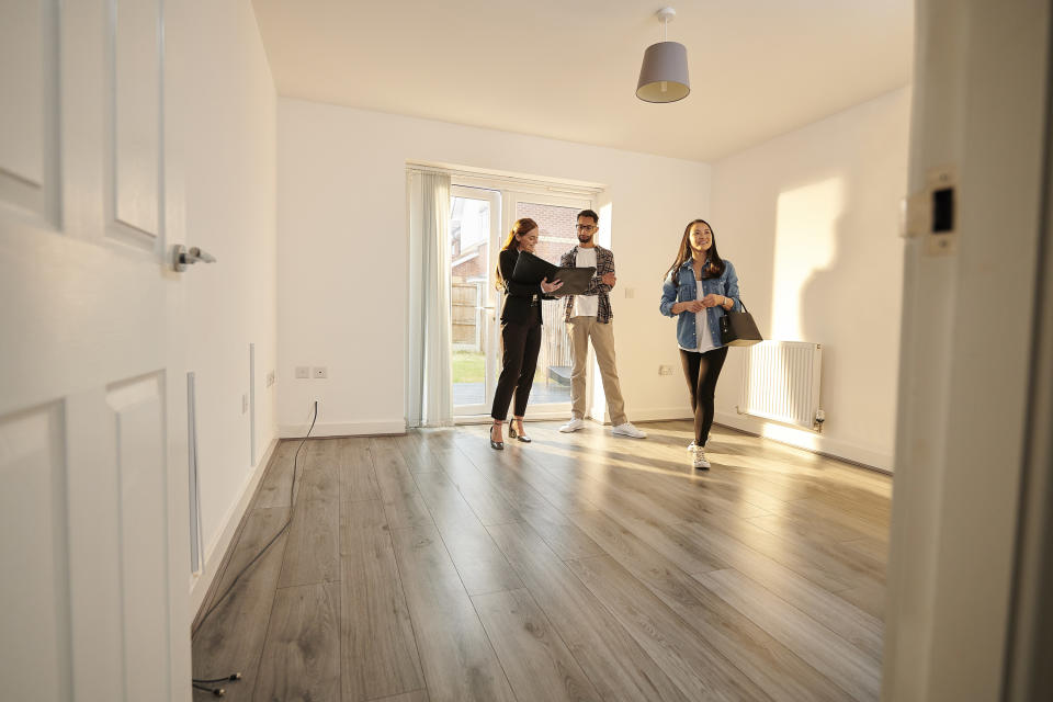 a couple and a realtor in an empty home