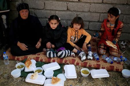 People who just fled Abu Jarbuah village sit as they eat at a Kurdish Peshmerga position between two front lines near Bashiqa, east of Mosul, Iraq October 29, 2016. REUTERS/Zohra Bensemra