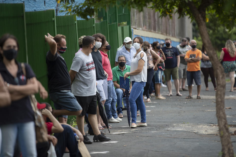 People wait in line outside a public school to get a shot of China&#39;s Sinovac CoronaVac vaccine in Serrana, Sao Paulo state, Brazil, Wednesday, Feb. 17, 2021. Brazil&#39;s Butantan Institute has started a mass vaccination on Wednesday of the city&#39;s entire adult population, about 30,000 people, to test the virus&#39; behavior in response to the vaccine. (AP Photo/Andre Penner)