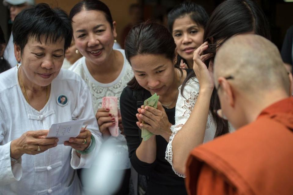 Women receive alms from family and friends in Bangkok after their families shaved their heads in a ceremony upon entering monastic life. <a href="https://www.gettyimages.com/detail/news-photo/thai-newly-ordained-female-buddhist-monks-receive-their-news-photo/665240960?adppopup=true" rel="nofollow noopener" target="_blank" data-ylk="slk:Roberto Schmidt/AFP via Getty Images;elm:context_link;itc:0;sec:content-canvas" class="link ">Roberto Schmidt/AFP via Getty Images</a>