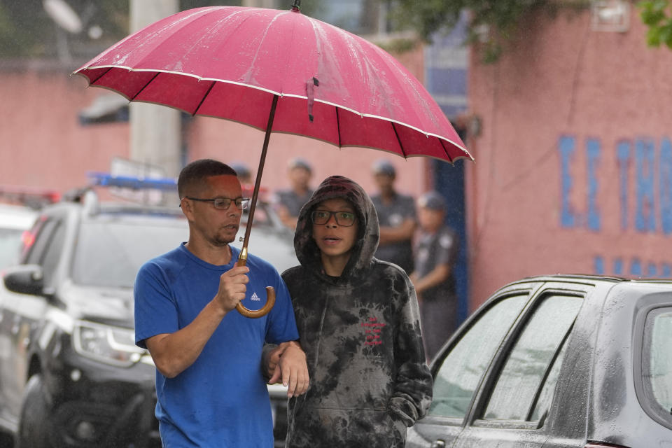 A student leaves the Thomazia Montoro school with his father after a fatal stabbing at the school in Sao Paulo, Brazil, Monday, March 27, 2023. A 13-year-old student fatally stabbed a 71-year-old teacher and wounded three teachers and two fellow students Monday in a knife attack at the public school, state officials said. (AP Photo/Andre Penner)