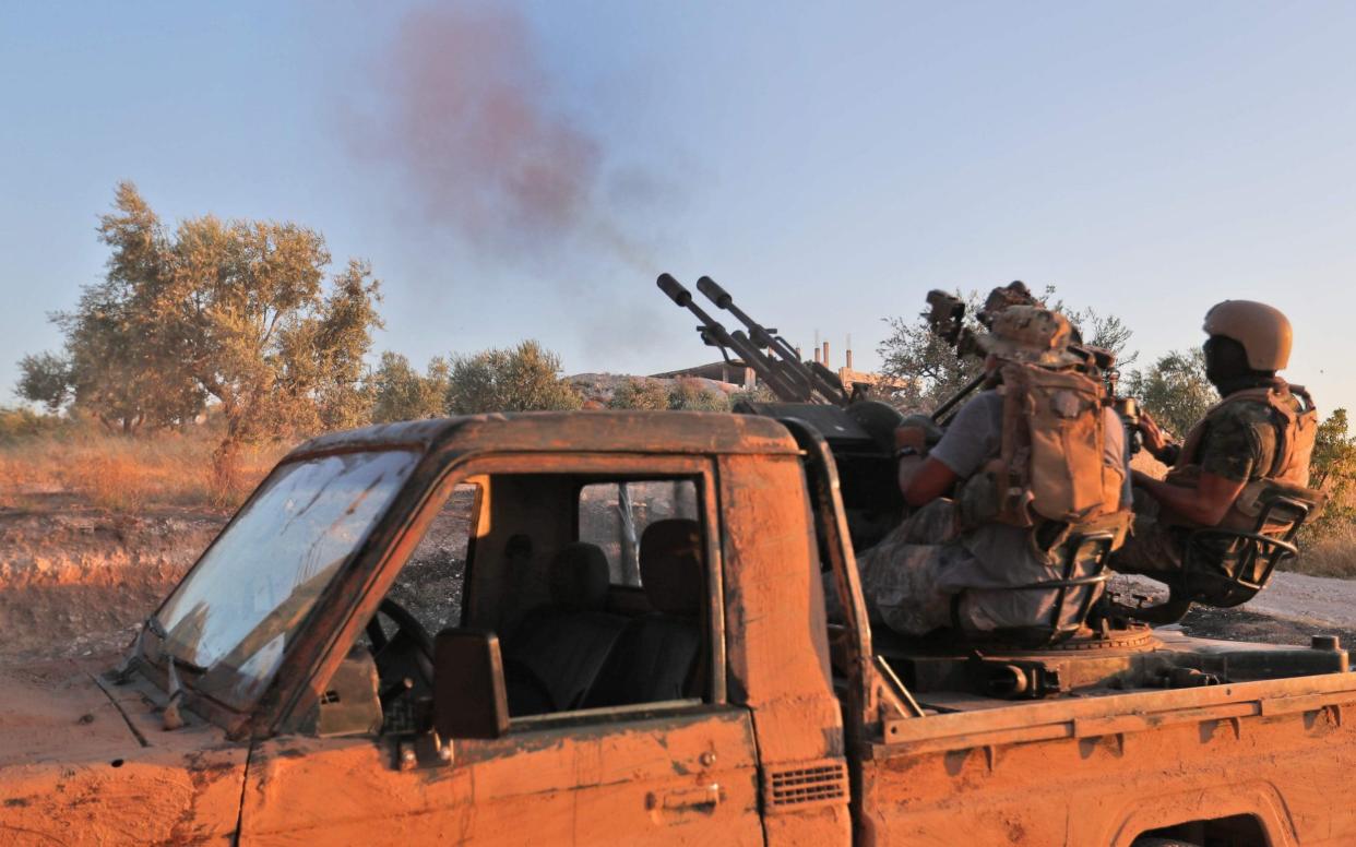 A fighter from the former al-Qaeda Syrian affiliate Hayat Tahrir al-Sham (HTS) fires an anti-aircraft gun mounted on a pickup truck in Syria's southern Idlib province - AFP