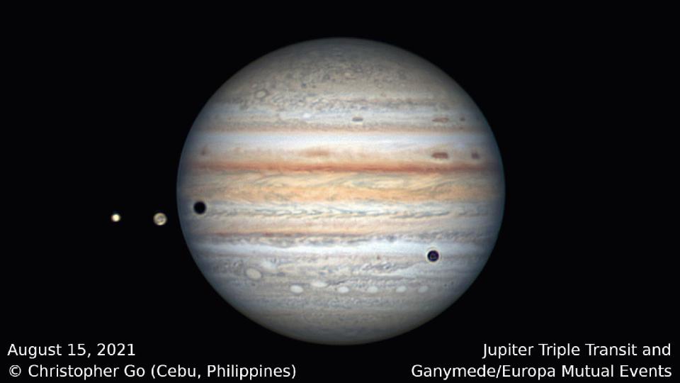 jupiter rotating as three moons pass in front of it casting shadows on jupiter