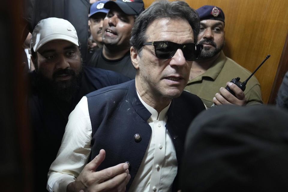 Former Pakistani Prime Minister Imran Khan, center, leaves court after an appearance in Lahore, Pakistan, Friday, May 19, 2023. Khan dialed down his campaign of defiance on Friday, saying he would allow a police search of his home over allegations that he was harboring suspects wanted in recent violence during anti-government protests by his supporters. (AP Photo/K.M. Chaudary)