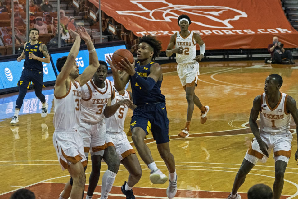 West Virginia guard Miles McBride (4) drives the ball against Texas forward Brock Cunningham (30) during the first half of an NCAA college basketball game, Saturday, Feb. 20, 2021, in Austin, Texas. (AP Photo/Michael Thomas)