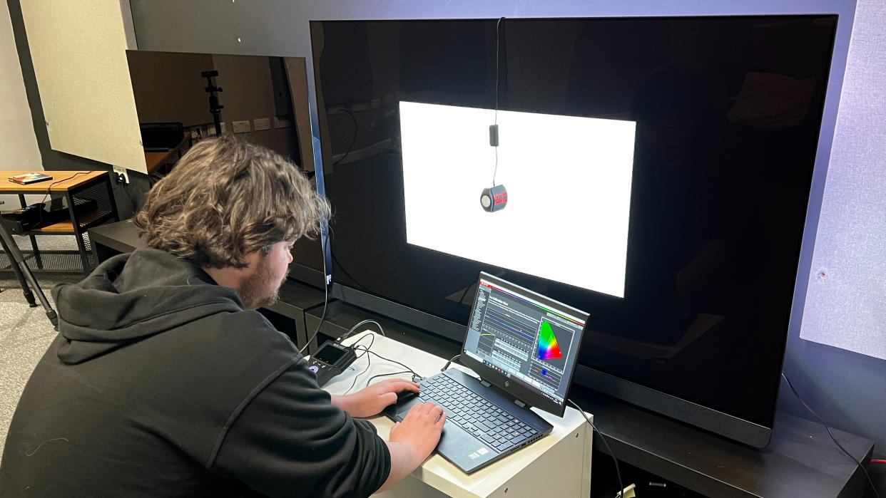  TechRadar reviewer measuring TV brightness with test equipment. 