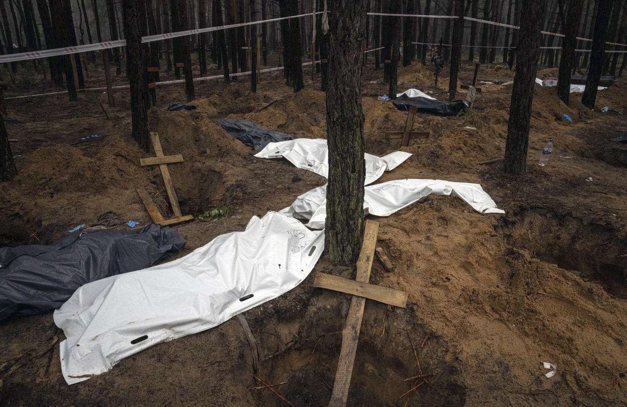 Bags with dead bodies are seen during the exhumation in the recently retaken area of Izium, Ukraine, Friday, Sept. 16, 2022. Ukrainian authorities discovered a mass burial site near the recaptured city of Izium that contained hundreds of graves. It was not clear who was buried in many of the plots or how all of them died, though witnesses and a Ukrainian investigator said some were shot and others were killed by artillery fire, mines or airstrikes. (AP Photo/Evgeniy Maloletka)