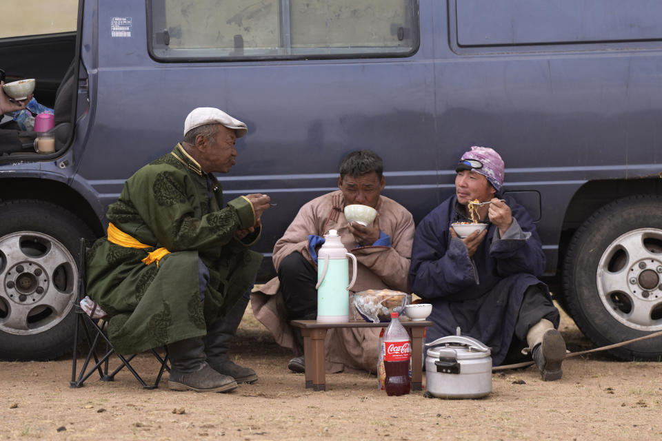 Herder Lkhaebum, left, talks to his assistant herders as they take a tea break on their way to settle in a new location in the Munkh-Khaan region of the Sukhbaatar district in southeast Mongolia, Saturday, May 14, 2023. (AP Photo/Manish Swarup)