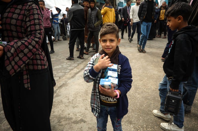 Displaced Palestinians receive food aid at the United Nations Relief and Works Agency for Palestine Refugees school in Rafah in the southern Gaza Strip on Sunday. Photo by Ismael Mohamad/UPI