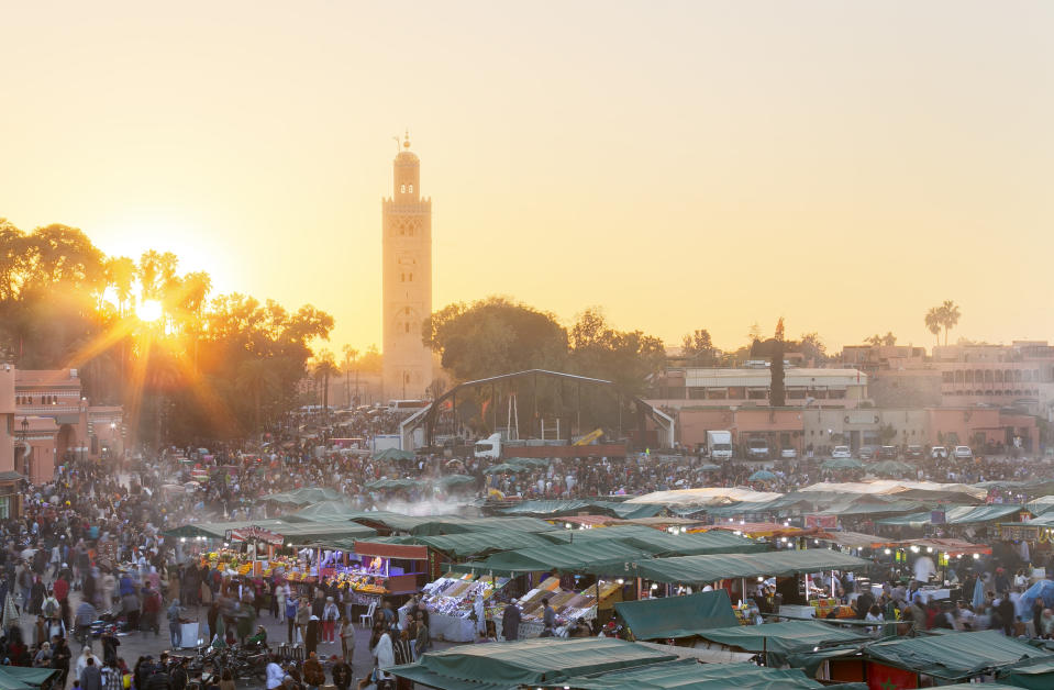 Sunset over a bustling market square with a tall tower in the background