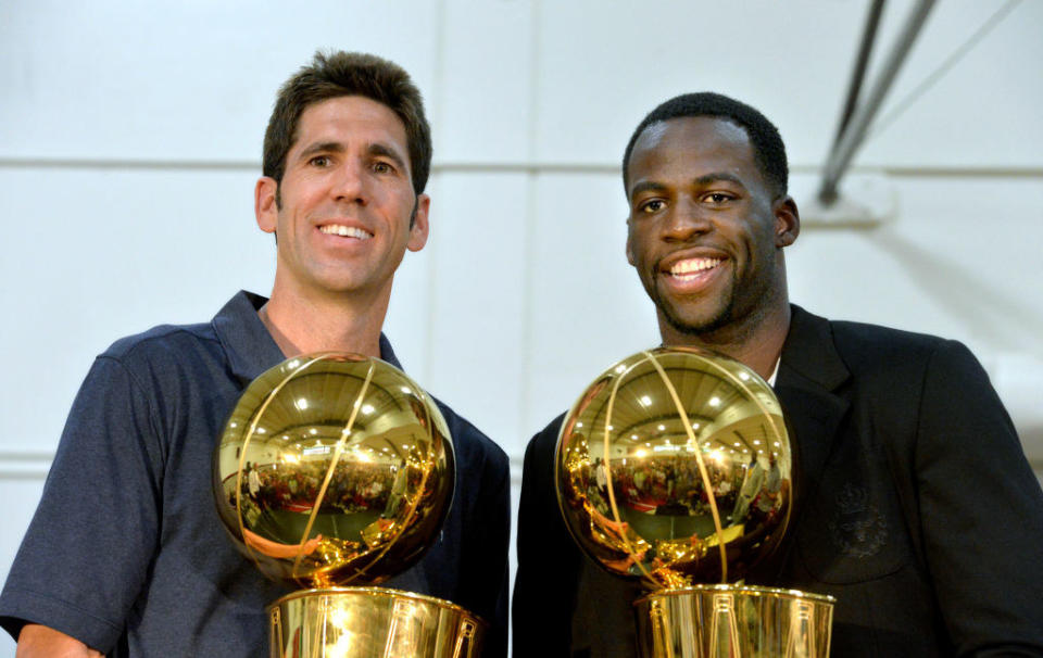 Bob Myers and Draymond Green holding the Golden State Warriors' 2017 and 2015 Larry O'Brien NBA Championship Trophies