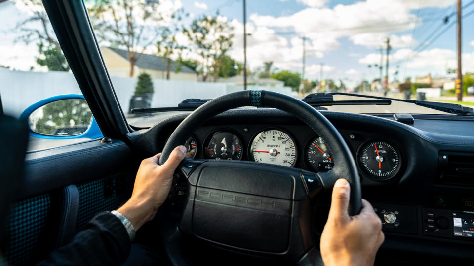 A close-up of hands on the steering wheel of an all-electric Porsche 964 restomod from Everrati.