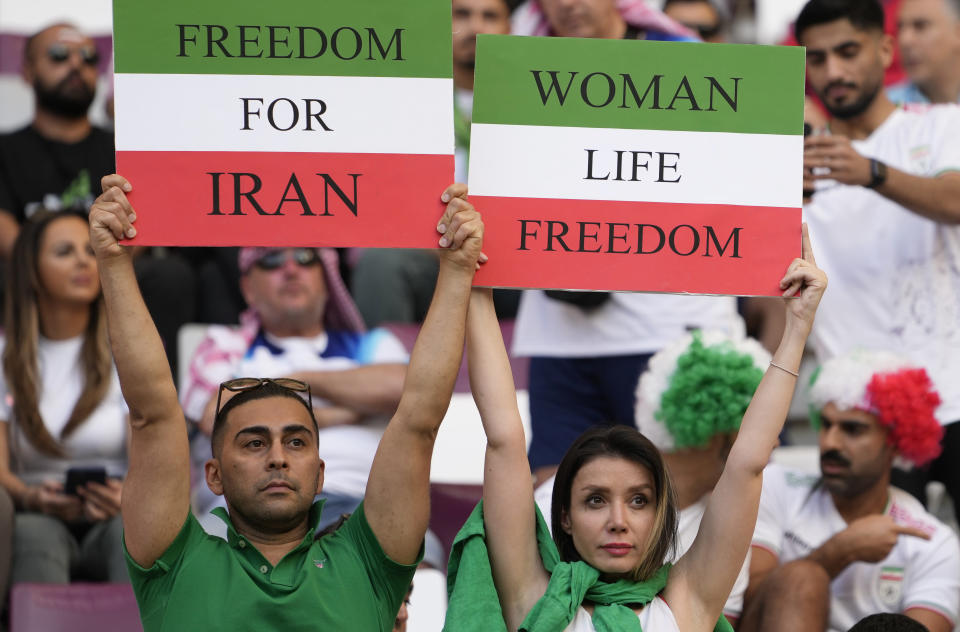 Iranian soccer fans hold up signs reading Woman Life Freedom and Freedom For Iran, prior to the World Cup group B soccer match between England and Iran at the Khalifa International Stadium in in Doha, Qatar, Monday, Nov. 21, 2022. (AP Photo/Alessandra Tarantino)