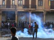 Demonstrators run from tear gas during ongoing anti-government protests in Baghdad