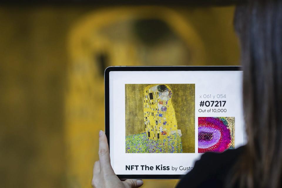 over-the-shoulder view of a person holding a tablet displaying an image of a painting