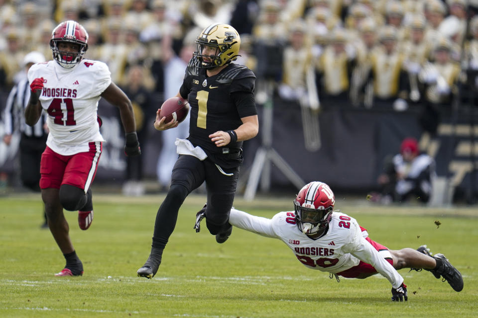 Indiana defensive back Louis Moore (20) dives to tackles Purdue quarterback Hudson Card (1) during the first half of an NCAA college football game in West Lafayette, Ind., Saturday, Nov. 25, 2023. (AP Photo/Michael Conroy)