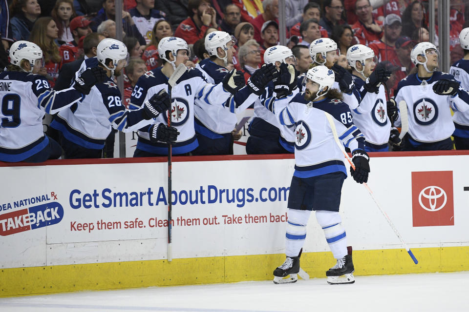 Winnipeg Jets left wing Mathieu Perreault (85) celebrates his goal with the bench during the first period of an NHL hockey game against the Washington Capitals, Sunday, March 10, 2019, in Washington. (AP Photo/Nick Wass)