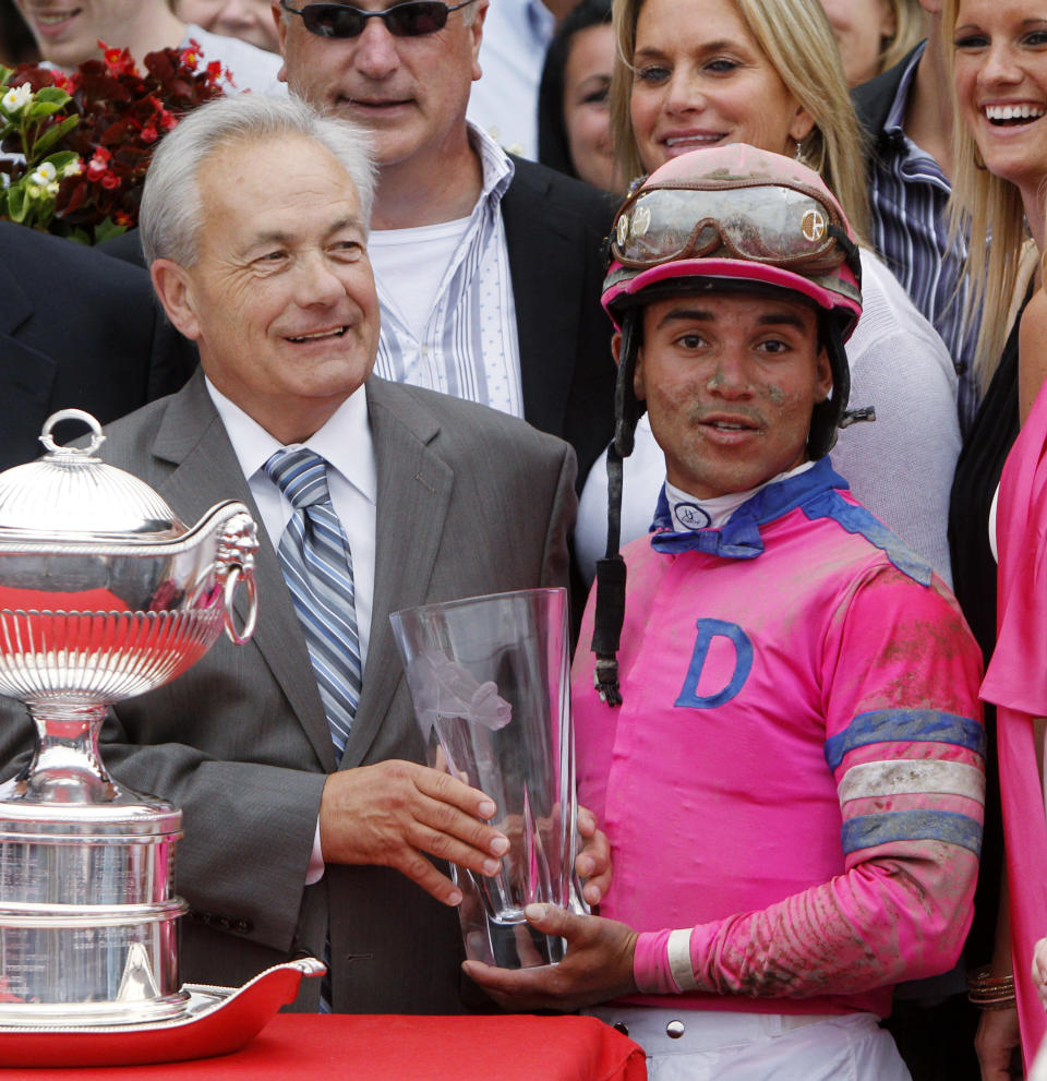 FILE - In this Aug. 21, 2010, file photo, Jockey Joel Rosario, right, and trainer Jerry Hollendorfer pose with trophies after Rosario rode Blind Luck to a win in the Alabama Stakes horse race at Saratoga Race Course in Saratoga Springs, N.Y. Hall of Fame trainerHollendorfer was banned by the ownership of Santa Anita on Saturday, June 22, 2019, after a fourth horse from his stable died--and the 30th overall--at the Southern California track. (AP Photo/Mike Groll, File)