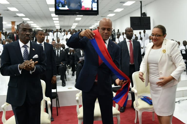 Haitian President Michel Martelly (C) takes off his presidential sash during a ceremony in parliament in Port-au-Prince on February 7, 2016