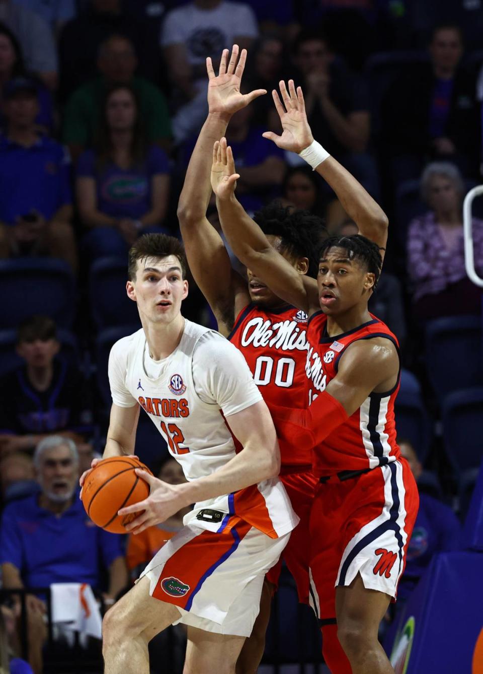 Florida Gators forward Colin Castleton (12) passes the ball as Mississippi Rebels guard Matthew Murrell (11) and Mississippi Rebels forward Jayveous McKinnis (00) defend during the first half Feb. 15, 2023, at Exactech Arena in Gainesville, Florida.