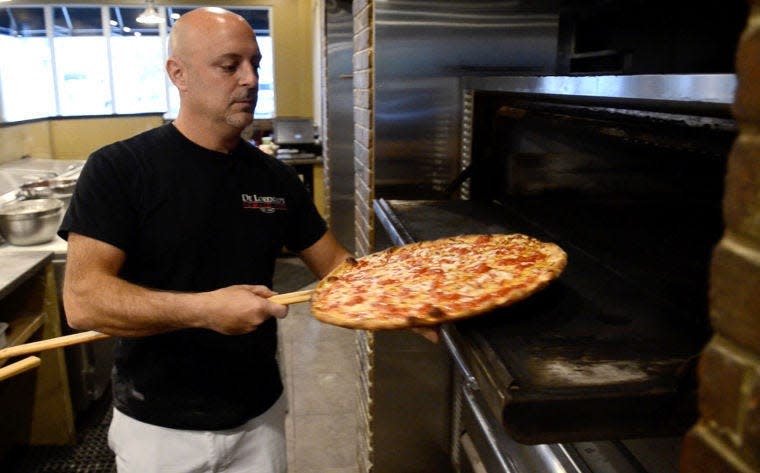 Sam Amico, owner of De Lorenzo's Tomato Pies in Robbinsville, removes a fresh Trenton tomato pie from the oven.
