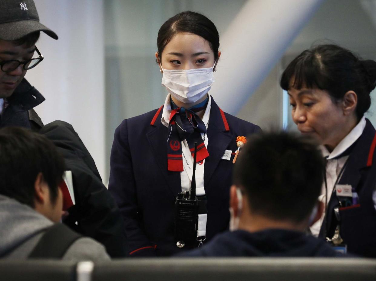 A Japan Airlines worker wears a face mask wile working inside a terminal at Los Angeles International Airport on Thursday: Getty Images