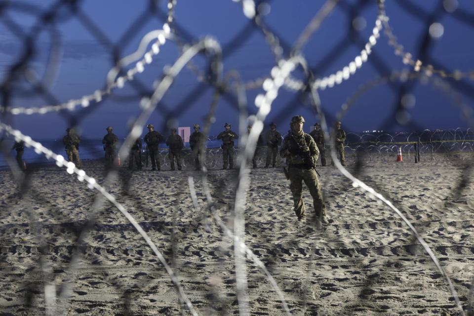 U.S. Border Patrol agents are seen though the border structure from the Mexican side at the Pacific Ocean, Tijuana, Mexico, Friday, Nov. 16, 2018. As thousands of migrants in a caravan of Central American asylum-seekers converge on the doorstep of the United States, what they won't find are armed American soldiers standing guard. (AP Photo/Rodrigo Abd)