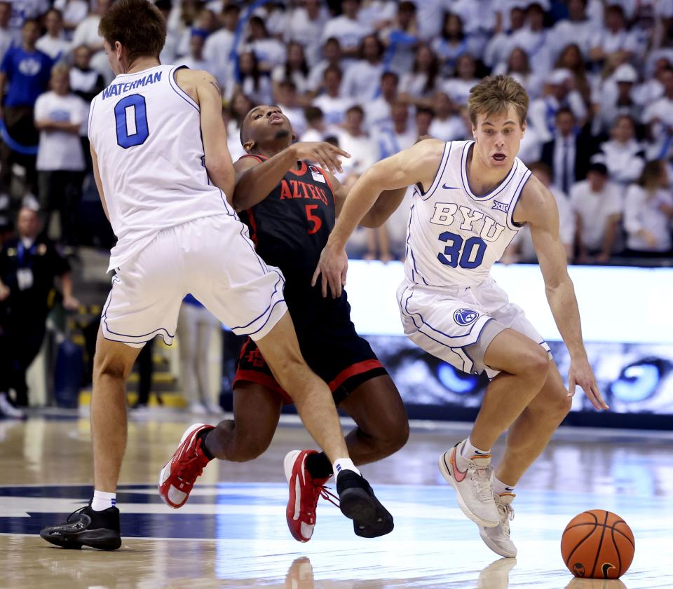 Brigham Young Cougars forward Noah Waterman (0) fouls San Diego State Aztecs guard Lamont Butler (5) as Brigham Young Cougars guard Dallin Hall (30) drives to the basket at BYU’s Marriott Center in Provo on Friday, Nov. 10, 2023. | Laura Seitz, Deseret News