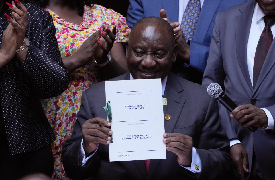 South African President Cyril Ramaphosa shows the signed bill for National Health Insurance signed into law in Pretoria, South Africa, Wednesday, May 15, 2024. Cyril Ramaphosa on Wednesday signed into law a new health bill that aims to overhaul the country’s healthcare system but is set to face legal challenges from opposition parties. (AP Photo/The,ba Hadebe)