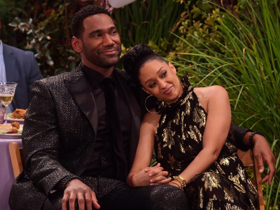 Tia Mowry and Anthony Alabi at an outdoor party sitting in chairs in "Family Reunion"