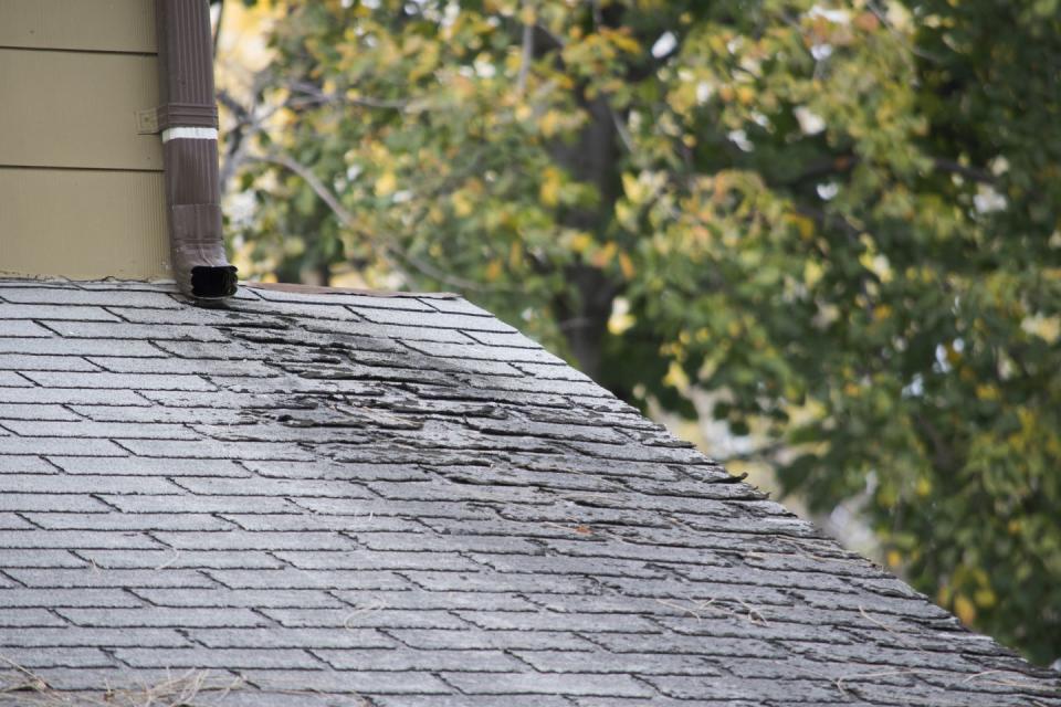 damaged and old roofing shingles on a house