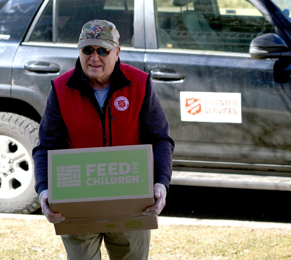 Salvation Army volunteer Mike Williams carries a box of supplies from his SUV for delivery to quarantined people during the coronavirus outbreak on March 26 in Avon, Colo.