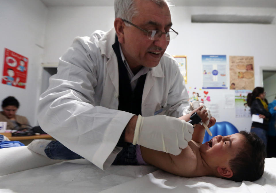 In this Tuesday, March 11, 2014 photo, Dr. Darwish Khan examines two year-old Syrian refugee Mohammed al-Omar at a medical clinic in the town of Kab Elias in Lebanon's Bekaa Valley. Three years after Syria’s uprising began to overthrow President Bashar Assad, spiraling into a war that has killed over 140,000 people and sending over 2.5 million people fleeing into neighboring countries, aid workers say are now seeing malnutrition emerge, once a barely known scourge in Syrian society. (AP Photo/Bilal Hussein)