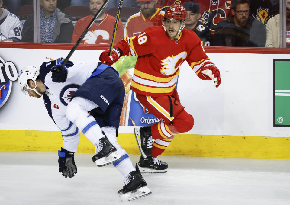 Winnipeg Jets forward Gabriel Vilardi, left, stumbles as Calgary Flames forward A.J. Greer watches during the second period of an NHL hockey game Wednesday, Oct. 11, 2023, in Calgary, Alberta. (Jeff McIntosh/The Canadian Press via AP)