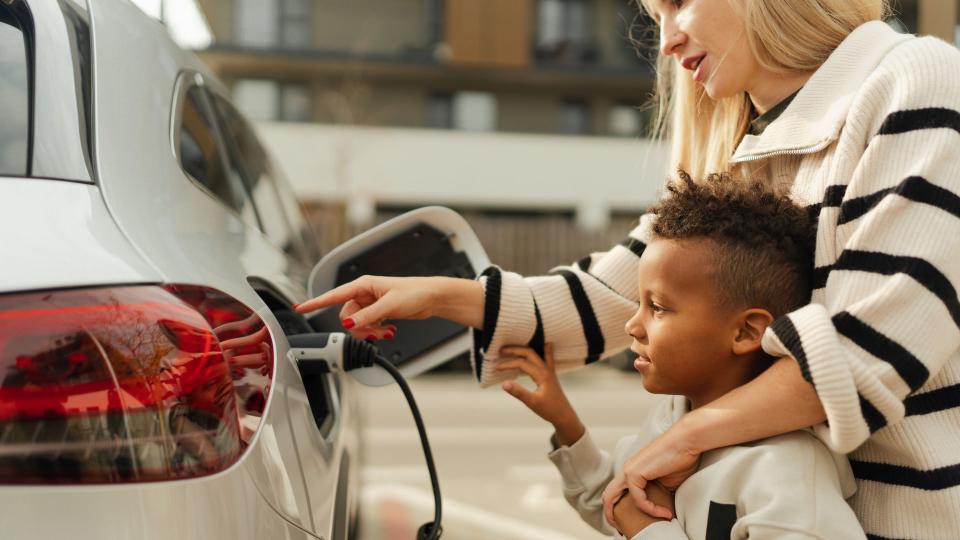 Close-up of mother with her son charging their electric car during autumn day.