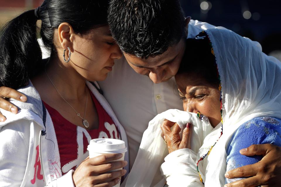 In this Aug. 6, 2012, file photo Amardeep Kaleka, son of the president of the Sikh Temple of Wisconsin, center, comforts members of the temple in Oak Creek, Wis.  Satwant Kaleka, 65, founder and president of the temple, died in the shooting. He was among four priests who died. Aug 5 is the one-year anniversary of the shooting. (AP Photo/M. Spencer Green, File)