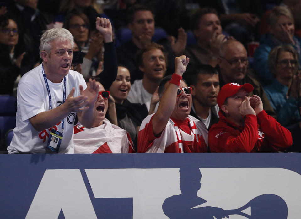 Former British Speaker of the House of Commons John Bercow, left, applauds Switzerland's Roger Federer as he walks onto the court to playa against Austria's Dominic Thiem in their ATP World Tour Finals doubles tennis match at the O2 Arena in London, Sunday, Nov. 10, 2019. (AP Photo/Alastair Grant)