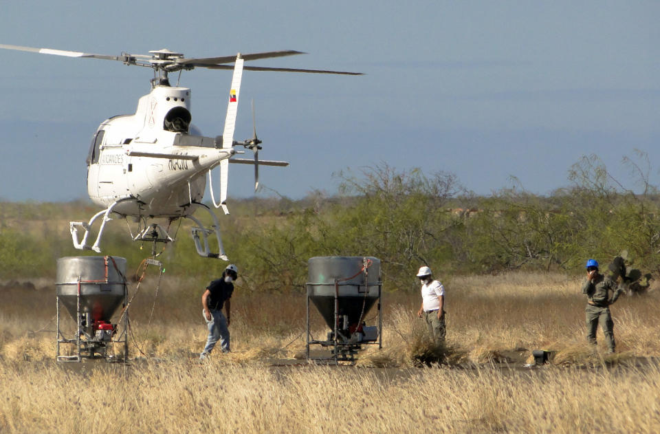 In this Nov. 11, 2012 photo released by Galapagos National Park, park staff test equipment that will hold poisonous bait to kill rats on the Galapagos Islands, as they stand on Baltra Island. To preserve the unique birds, reptiles and native plants that make the Galapagos Islands such an ecological treasure, authorities will start on Wednesday, Nov. 14, 2012 phase II of a mass kill-off of black and Norway rats, an invasive species introduced to the Pacific Ocean islands by whalers and buccaneers beginning in the 17 century. (AP Photo/Galapagos National Park)