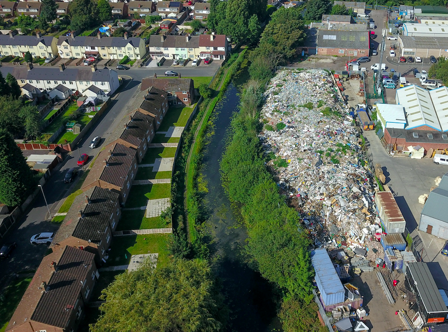 The towering pile of waste has now grown higher than nearby trees and houses. (SWNS)