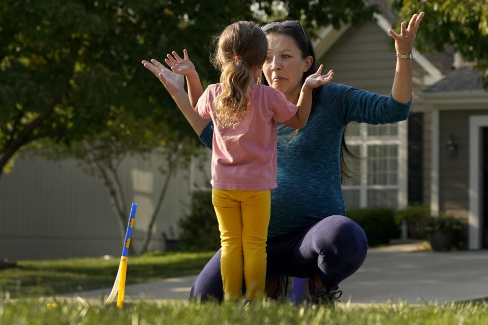 Claire Reagan plays with her daughter Abbie, 3, Monday, Sept. 21, 2020, outside her home in Olathe, Kan. Reagan is keeping her son Evan, 5, from starting kindergarten and her daughter from preschool due to concerns about the coronavirus pandemic. (AP Photo/Charlie Riedel)