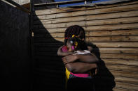 Develine, born in the Republic Dominican to Haitian parents, holds her two-year-old, Chilean-born sister Cataleya, outside their home where they live with their mother Magdaline Afred, who has permanent Chilean residency, in Santiago's Dignidad camp set up by migrants in Chile, Thursday, Sept. 30, 2021. There are 180,000 Haitians in Chile, of whom “almost 70,000 reside in the country permanently,” said deputy interior minister Juan Francisco Galli. (AP Photo/Esteban Felix)