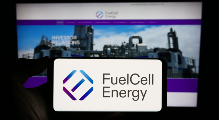 Person holding cellphone with logo of US fuel cell company FuelCell Energy Inc. (FCEL) on screen in front of business webpage. Focus on phone display. Unmodified photo.