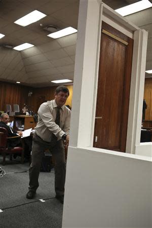 A policeman demonstrates the effect of hitting a bathroom door with a cricket bat during the trial of South African Paralympic athlete Oscar Pistorius in the North Gauteng High Court in Pretoria, March 12, 2014. REUTERS/Alexander Joe/Pool