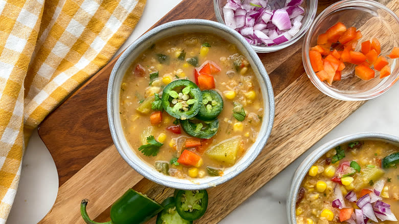 Small bowl of corn chowder next to raw garnishes