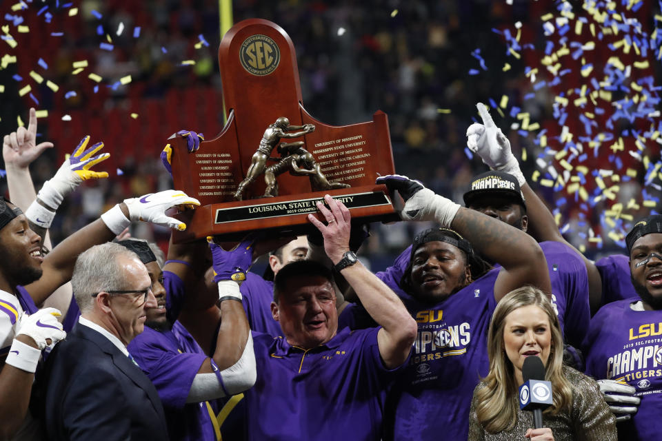 LSU head coach Ed Orgeron and team members celebrate with teammates after the Southeastern Conference championship NCAA college football game against Georgia, Saturday, Dec. 7, 2019, in Atlanta. LSU won 37-10. (AP Photo/John Bazemore)